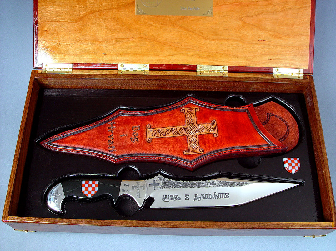 "Duhovni Ratnik" Knife in hand-engraved 440C high chromium stainless steel blade, hand-engraved 304 stainless steel bolsters, handle of Black Nephrite Jade gemstone inlaid with a mosaic of Red River Jasper and White Geodic Quartz. Sheath is hand-carved, hand-dyed leather shoulder