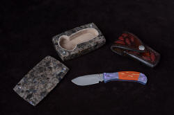 "Elysium" ensemble including fine handmade liner lock folding knife with gemstone handle and titanium bolsters and liners, hand-carved sheath inlaid with red rayskin, knife sarcophagus in polished anorthosite gemstone