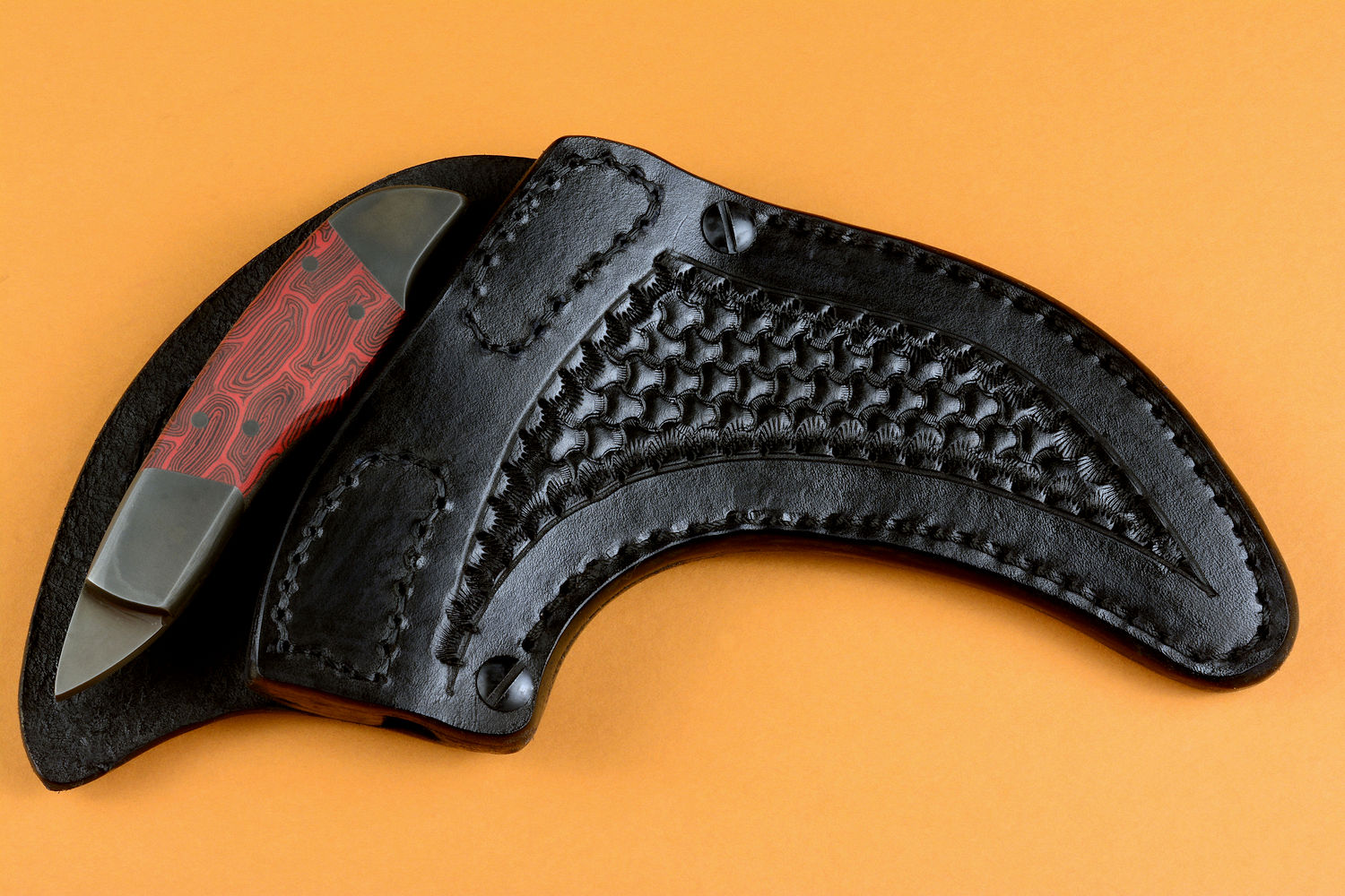 "Chela" karambit knife, post-lock leather sheath detail  in T4 cryogenically treated 440C high chromium martensitic stainless steel blade, 304 stainless steel bolsters, red and black tortoiseshell G10 composite handle, leather sheath with stainless steel and nylon