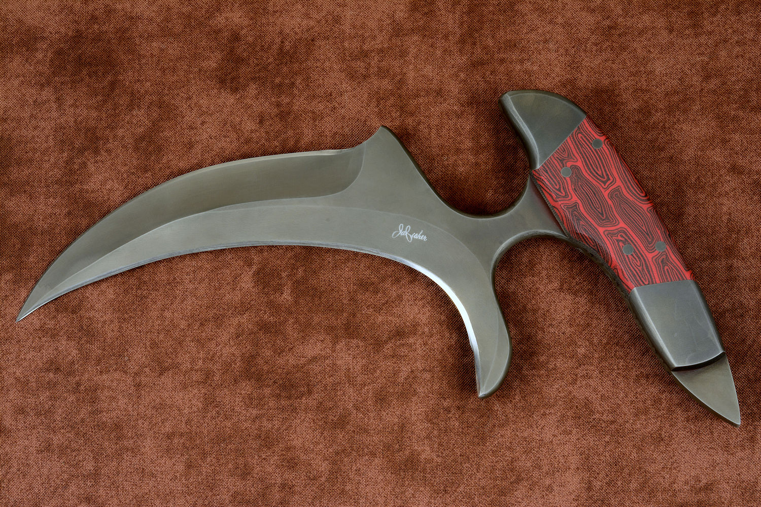 "Chela" karambit knife, obverse side view in T4 cryogenically treated 440C high chromium martensitic stainless steel blade, 304 stainless steel bolsters, red and black tortoiseshell G10 composite handle, leather sheath with stainless steel and nylon