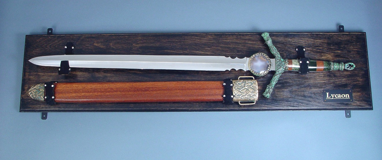 "Lycaon" handmade custom broadsword, mounted view  in 440C high chromium stainless steel blade, cast bronze fittings, guayabillo hardwood and nephrite jade gemstone handle, obsidian pommel, lauan hardwood scabbard with cast bronze chape, display board of ebonized red oak, steel, black suede, American Black Walnut, engraved black lacquered brass