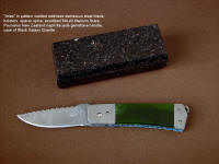 "Aries" folding knife, obverse side view in damascus stainless steel blade and bolsters, anodized titanium liners, New Zealand Jade gemstone handle, Black Galaxy Granite gemstone case