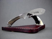 "The Cattleman" in etched 440C high chromium stainless steel blade, 304 hand-engraved stainless steel bolsters, petrified wood gemstone handle, cow horn and purpleheart (amaranth) hardwood base
