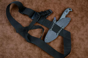 "Contego" Counterterrorism Tactical Knife, sheathed view, mounted to Sternum Harness Plus, in T3 cryogenically treated CPM154CM  powder metal technology high molybdenum martensitic stainless steel blade, 304 stainless steel bolsters, Black/Gray G10 fiberglass/epoxy composite handle, hybrid tension tab-locking sheath in kydex, anodized aluminum, stainless steel, titanium